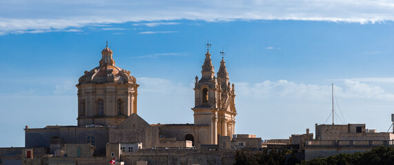 Warm afternoon light illuminates Mdina, Malta, with St. Paul's Cathedral dome and twin bell towers...