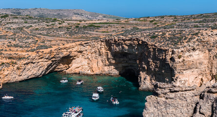 Aerial midday view of Comino Island Blue Lagoon in Malta, with limestone cliffs, sea cave, tour...