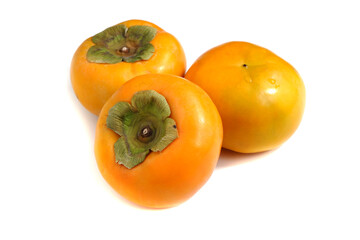 Close-up of three persimmon fruits on a white background
