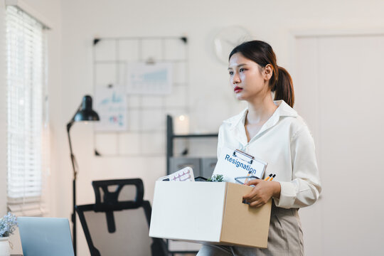 Sad businesswoman holding a box with resignation letter, leaving the office after quitting job
