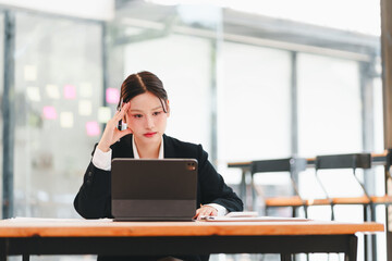 Fototapeta premium Stressed Asian woman worried about expenses, Financial problems, Calculating bills with phone and calculator at home office