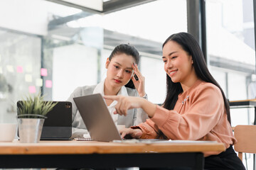 Young businesswoman and colleague collaborating on laptop in modern office, focused and engaged