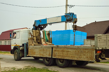 A truck-mounted crane with a load is standing on the road