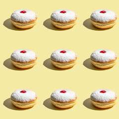 Seamless pattern of powdered donuts with cherry on yellow background