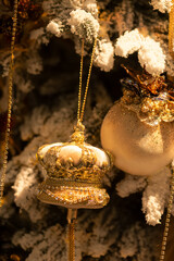 Golden crown and bauble Christmas ornaments on snowy tree branch
