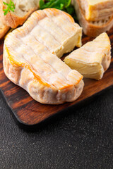 Washed rind cheese soft cheese with orange rind munster french cheese tasty snack fresh delicious gourmet food background on the table rustic top view copy space