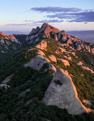 Naklejka premium Dramatic cliffs, clouds, soft fog and mountains at sunset, view of Montserrat landscape.