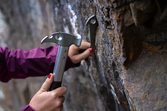 Female hands hold a climbing hammer and anchor.