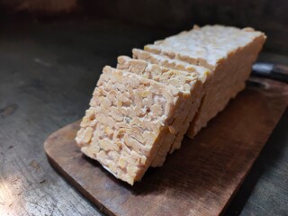 Raw tempeh slices on the wooden cutting board.