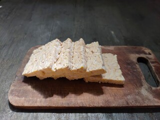 Raw tempeh slices on the wooden cutting board.