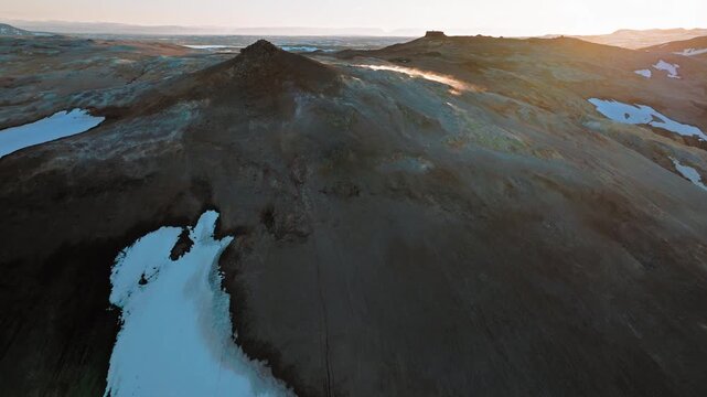 Wide aerial footage of Hverir geothermal area in North Iceland. The hot springs and fumaroles emit steam through colorful volcanic terrain.