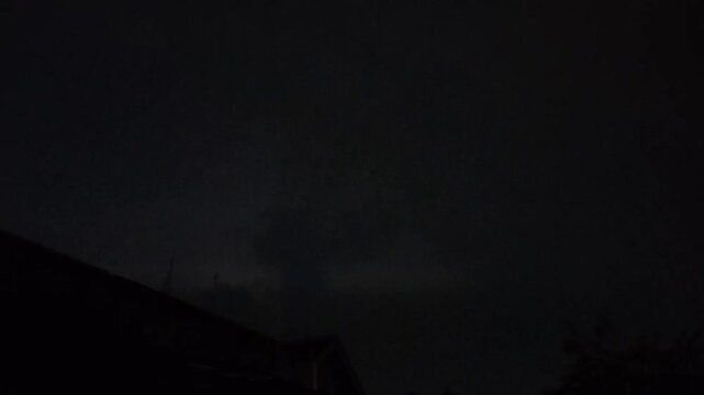 Dramatic Horizontal Lightning Bolt Flashing Across a Dark Stormy Night Sky with Visible Power Lines, Signifying Storm and Electric Power