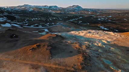 Drone shot of Hverir geothermal area in North Iceland. The camera captures steam vents surrounded by volcanic soil and distant snow. - Powered by Adobe