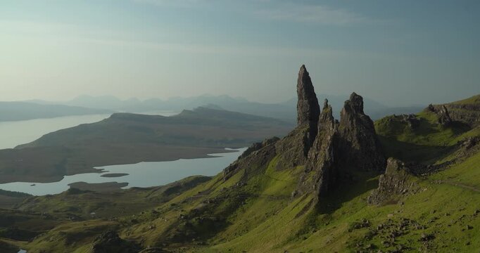 The Old Man of Storr on the Isle of Skye in Scotland, with natural light, dominating the hill going to the ocean, with a lake inbetween