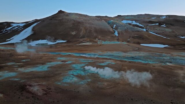 Drone view of Hverir geothermal area in North Iceland. Hot springs and fumaroles emit white steam across the mineral landscape.