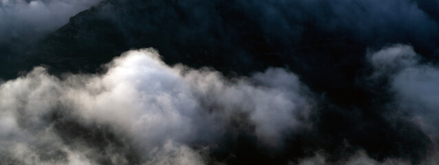 Obraz premium Beautiful landscape with mountains among fog and clouds at sunset.