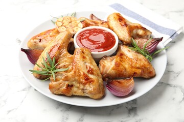 Delicious grilled chicken wings served on white marble table, closeup