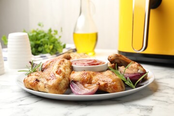 Delicious grilled chicken wings with sauce, spices and air fryer on white marble table, closeup