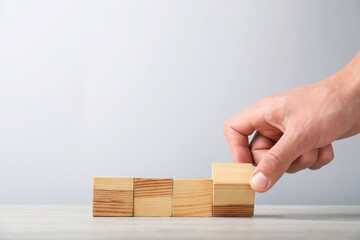 Man with wooden cubes on light background, closeup. Space for text