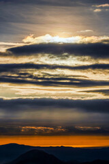 Fototapeta premium Beautiful landscape with mountains among fog and clouds at sunset.