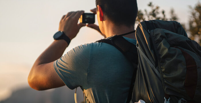 A man holding an action camera a in his hands, makes photo of mountains..
