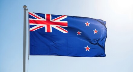 A flag of New Zealand with a blue field and red and white stars against a clear blue sky