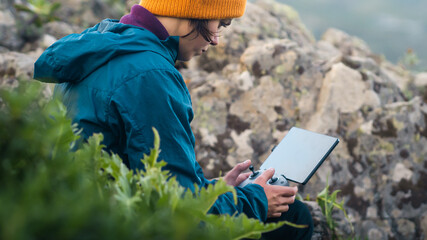 A girl travels and flights a drone, holds a remote control in her hands.