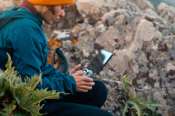 A girl travels and flights a drone, holds a remote control in her hands.
