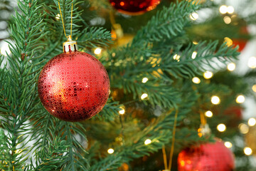 Christmas bauble hanging on fir tree branch against blurred lights, closeup with space for text. Bokeh effect