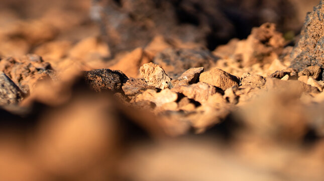 Stones and rocky lava formations on sandy desert terrain closeup.