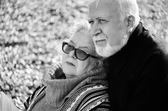 Elderly couple enjoying a peaceful moment together on a sunny day in a park surrounded by fallen leaves