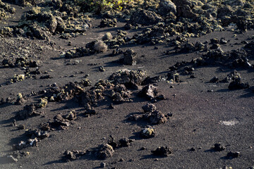 Black lava formations, basalt rocks closeup at the foot of a volcano.