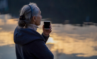 Fototapeta premium A woman, lady drinks a coffee and enjoys the sunset.