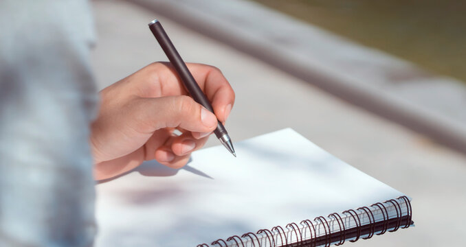 Man is writing notes on a white paper, hands closeup.