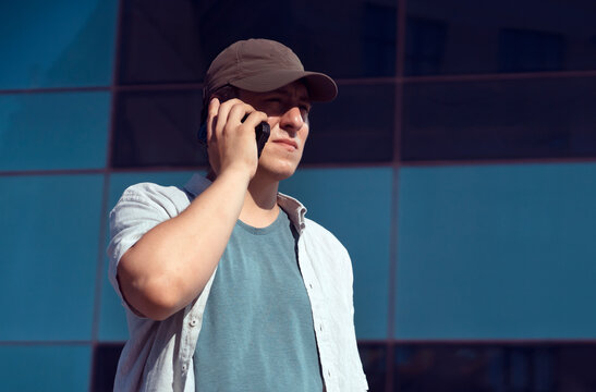 A man is holding a smartphone, walking in the city outdoors.