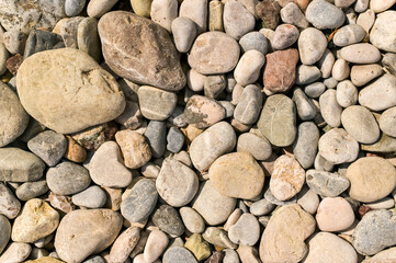 Colorful beach pebbles create textured background, pattern full of irregular shapes. Natural backdrop of seaside pebbles, rounded stones shaped by ocean. Pebbles define coastal detail and texture.
