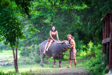 A farmer family is raising buffalo. Young people and buffalo.