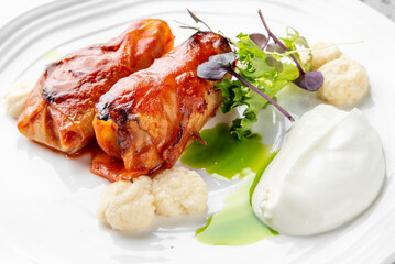 Gourmet dish with two chicken rolls, mashed potatoes, and greens on a white plate with a drizzle of green sauce. Modern, fine dining presentation