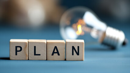 "PLAN" is spelled out in wooden blocks with a bright lightbulb. planning is key to new ideas and success.