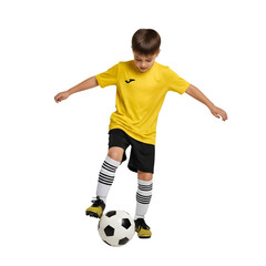 A young boy in a yellow jersey and black shorts dribbling a soccer ball with his feet on a black background