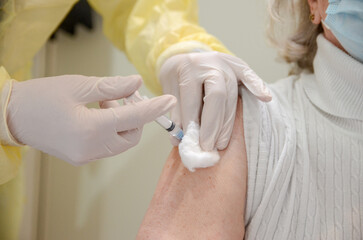 A nurse administers a vaccine to an elderly woman. Vaccination of the population. Vaccination against the COVID-19 virus during the coronavirus pandemic. Vaccine. Immunization of patients in hospital.
