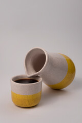 Minimalist scene of V60 brewed coffee poured into a handmade ceramic jug and cup with yellow detail, emphasizing artisanal design and slow-living coffee culture.