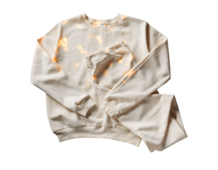 A cream colored silk pajama set with long sleeves and pants folded neatly isolated on transparent background