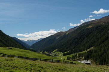 Weites Almtal mit grünen Wiesen und Bergkulisse in Südtirol