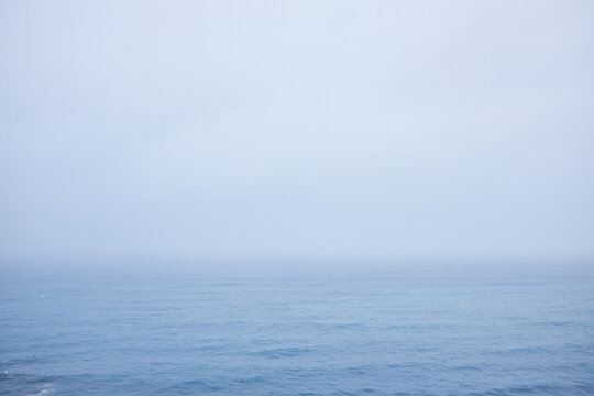 Mystical depiction of Atlantic Ocean: fog hovering over it and small waves on water surface, nothing seen on horizon