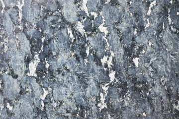 Celestial Dust: Close-Up of a Dark, Granular Stone Surface Speckled with Fine White and Blue Mineral Inclusions