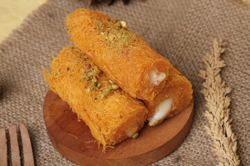 Traditional Middle Eastern kunafa rolls made with shredded phyllo dough, filled with cream, and garnished with crushed pistachios on top.
