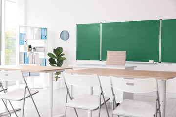 Green chalkboard and stylish furniture in classroom. Mockup for design