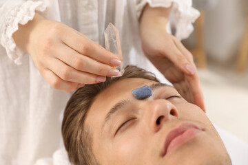 Man undergoing crystal therapy to heal or restore his aura indoors, closeup