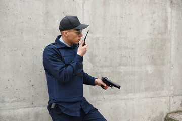 Police officer with radio and gun outdoors. Space for text